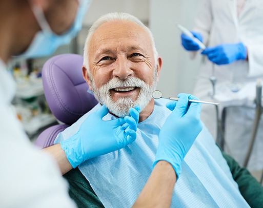 A dentist holding an upper denture in one hand and a lower denture in the other