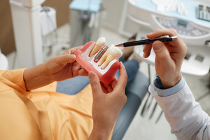 Dentist showing patient model of dental implant during consultation