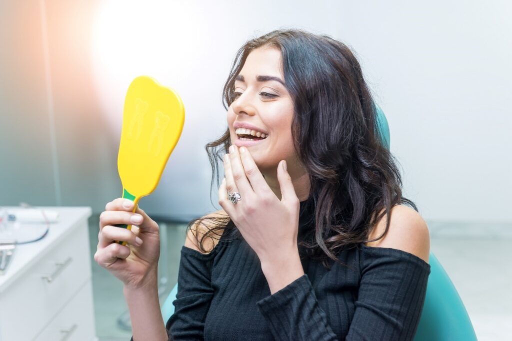 Smiling woman looking at reflection in yellow mirror